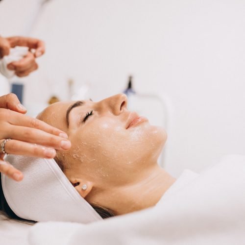 Cosmetologist cleaning face of a woman in a beauty salon