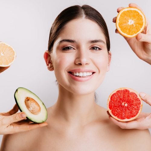 Healthy beautiful radiant skin of woman without makeup. Portrait of girl smiling against background of fruits